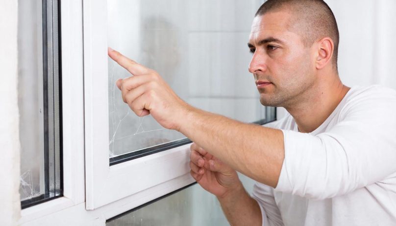 Мужчина осматривает раму окна